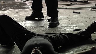 A still from Hunter, a man lies dead on his back, Hunter looming over him